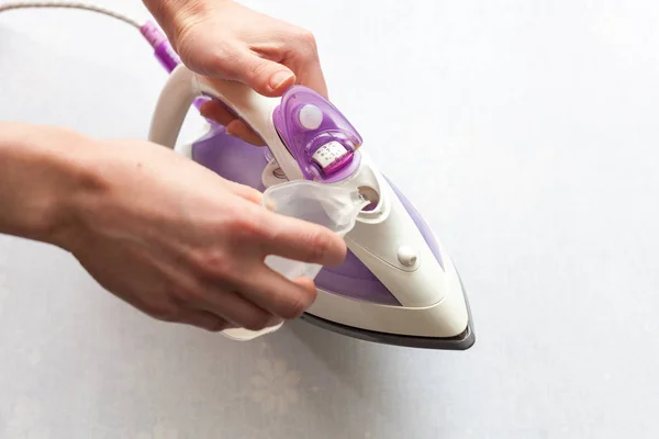 The girl pours distilled water into the tank of flat-iron. Top view during housework — Stock Photo, Image