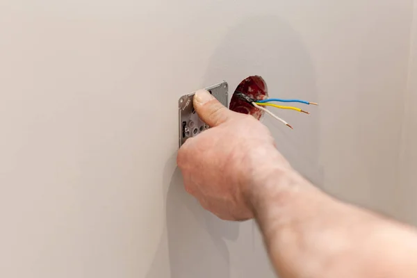 Les mains d'un électricien installant une prise de courant murale — Photo