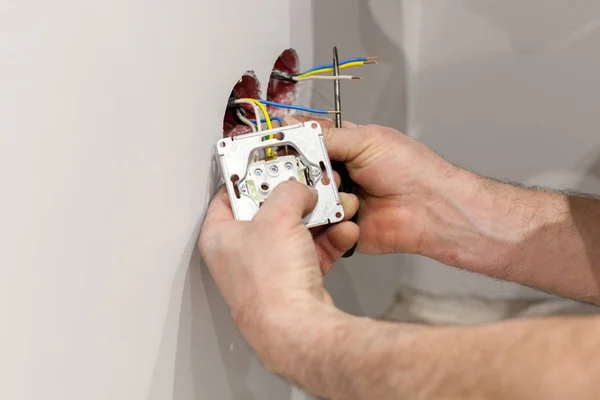 Les mains d'un électricien installant une prise de courant murale — Photo