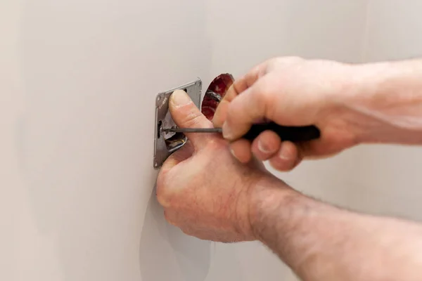 As mãos de um eletricista instalar uma tomada de energia de parede . — Fotografia de Stock