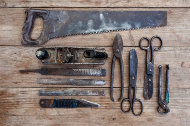 Görünüm vintage paslı eski ahşap masa üstünde alet: pense, boru anahtarı, tornavida, çekiç, metal makası, testere ve diğer