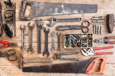 Görünüm vintage paslı eski ahşap masa üstünde alet: pense, boru anahtarı, tornavida, çekiç, metal makası, testere ve diğer