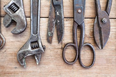 Görünüm vintage paslı eski ahşap masa üstünde alet: pense, boru anahtarı, tornavida, çekiç, metal makası, testere ve diğer