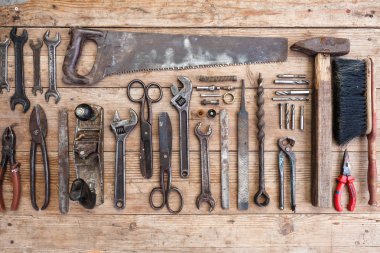 Görünüm vintage paslı eski ahşap masa üstünde alet: pense, boru anahtarı, tornavida, çekiç, metal makası, testere ve diğer