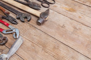 Görünüm vintage paslı eski ahşap masa üstünde alet: pense, boru anahtarı, tornavida, çekiç, metal makası, testere ve diğer