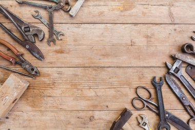 Görünüm vintage paslı eski ahşap masa üstünde alet: pense, boru anahtarı, tornavida, çekiç, metal makası, testere ve diğer