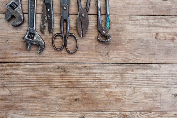 Ver herramientas oxidadas vintage en la mesa de madera vieja: alicates, llave de tubo, destornillador, martillo, cizallas de metal, sierras y otros —  Fotos de Stock