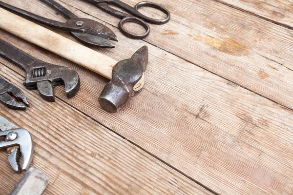 Ver herramientas oxidadas vintage en la mesa de madera vieja: alicates, llave de tubo, destornillador, martillo, cizallas de metal, sierras y otros —  Fotos de Stock