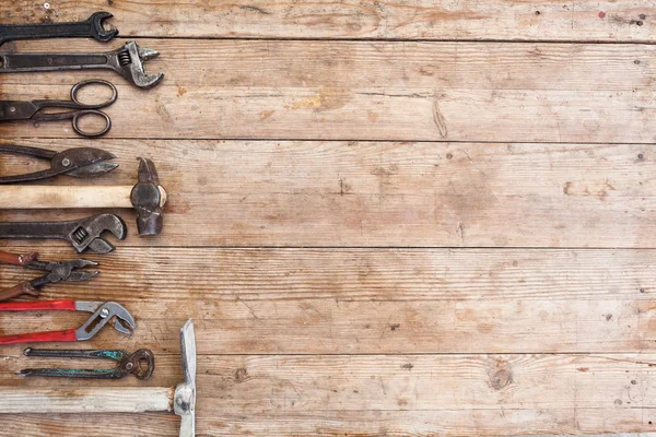 Ver herramientas oxidadas vintage en la mesa de madera vieja: alicates, llave de tubo, destornillador, martillo, cizallas de metal, sierras y otros —  Fotos de Stock