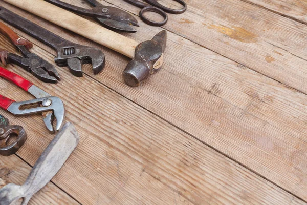 Görünüm vintage paslı eski ahşap masa üstünde alet: pense, boru anahtarı, tornavida, çekiç, metal makası, testere ve diğer
