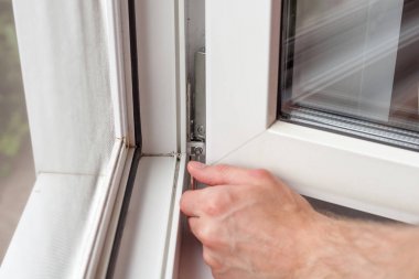 Tamirci bir Altıgen ile plastik pencere onarır. İşçi plastik pencere işlemi ayarlar.