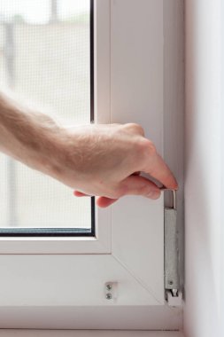 Tamirci bir Altıgen ile plastik pencere onarır. İşçi plastik pencere işlemi ayarlar.