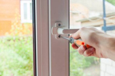 Tamirci plastik pencere tornavida ile onarır. İşçi plastik pencere işlemi ayarlar