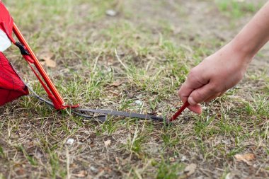  Kız closeup eller kırmızı kamp çadır yerleşimini, makro çekim peg ve çim
