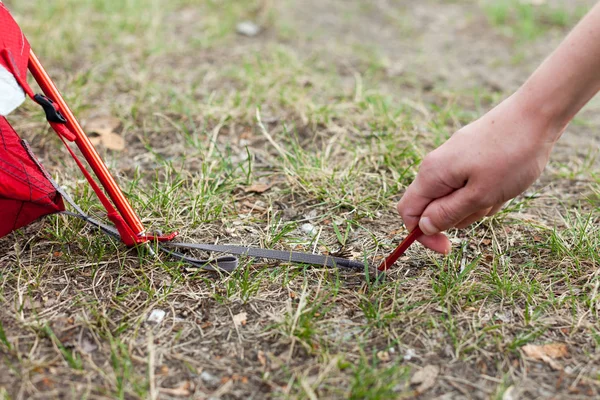  Kız closeup eller kırmızı kamp çadır yerleşimini, makro çekim peg ve çim