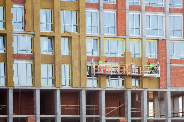 Construction workers insulating house facade with mineral rock wool installation. External wall insulation system (or EWIS) mineral wool for energy saving