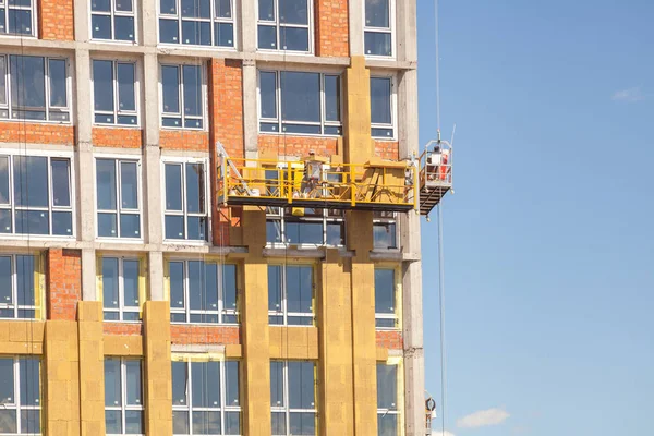 High-altitude work on the external walls of high-rise building. Glass wool insulation.