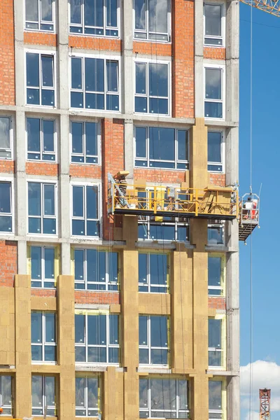 Construction workers insulating house facade with mineral rock wool installation. External wall insulation system (or EWIS) mineral wool for energy saving