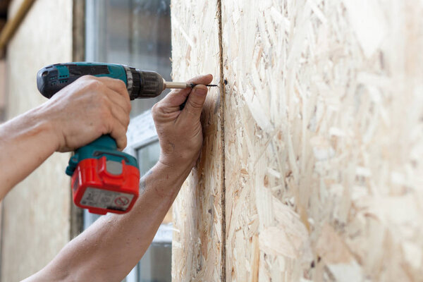 Construction worker use screwdriver to attach Wood Particle Board (fiberboard) to the wall