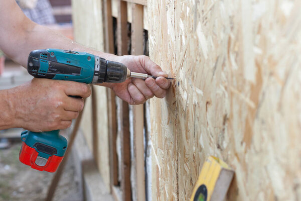 Construction worker use screwdriver to attach Wood Particle Board (fiberboard) to the wall