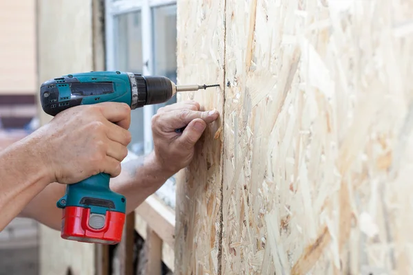 建筑工人用螺丝刀将木质板 纤维板 附着在墙上 — 图库照片