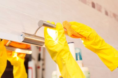 Sarı plastik koruyucu eldiven turuncu bez ile temizlik lamba ile eller. Kadın temiz burada ev