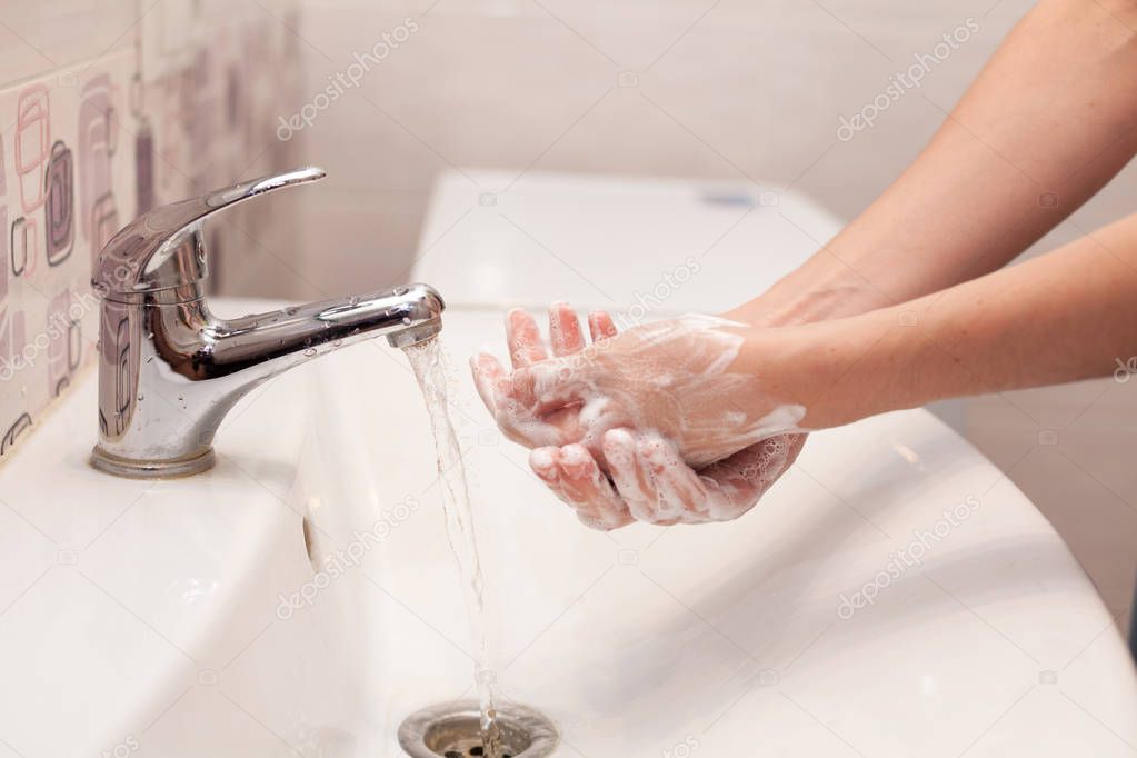 A woman is soaping her hands with soap. Hygiene. Washing hands in the bathroom