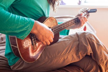 Genç bir adamın elleri bir akustik gitar ukulele evde oynarken closeup. Adam holding ukulele 