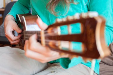 Genç adamın elleri bir akustik gitar ukulele evde oynarken. Görünümü kadar yakın ukulele oynayan bir adam.