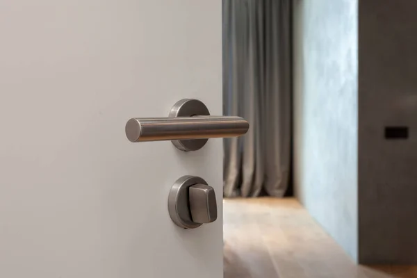 Open white door with metallic handle. The door to the bedroom