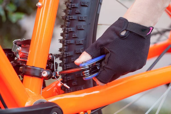 A hand in a bicycle glove with a multitool twists repairs the speed selector. Element of a bicycle.