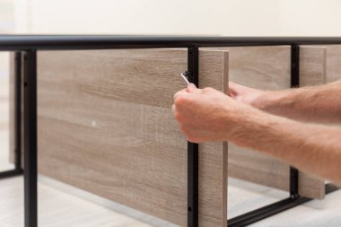 Genç bir adam onun oda iç için bir kitaplık gözlenmektedir. Tamirci bir Altıgen yardımıyla raf Raf takılır