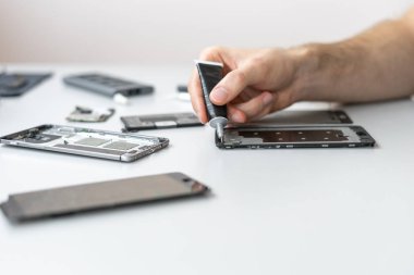 Hizmet merkezinde modern akıllı telefonu tamir eden adam.