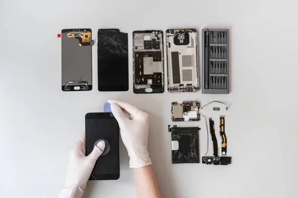 Человек ремонтирует современный смартфон в сервисном центре — стоковое фото
