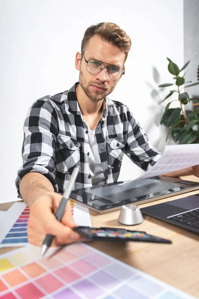 Young adult illustrator working with graphic tablet in office