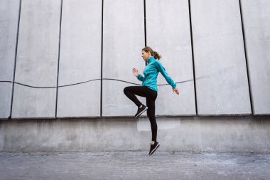 Genç sporcu kadın dışarıda duvara karşı zıplıyor.