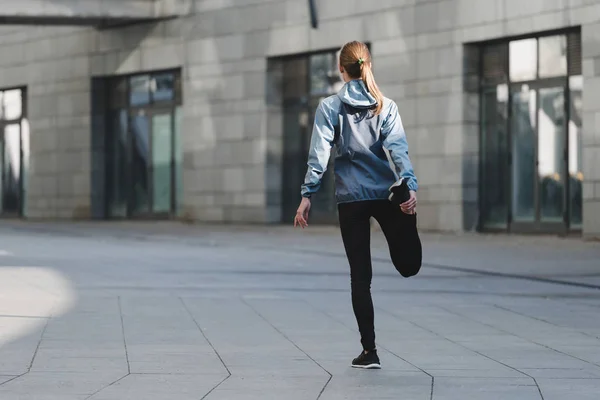 Jonge volwassen sportvrouw strekkende benen voor het uitvoeren van training — Stockfoto