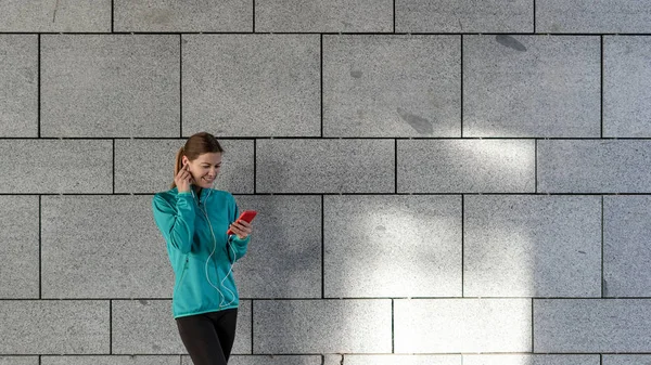 Jonge volwassen sportvrouw die muziek luistert na het trainen buiten — Stockfoto