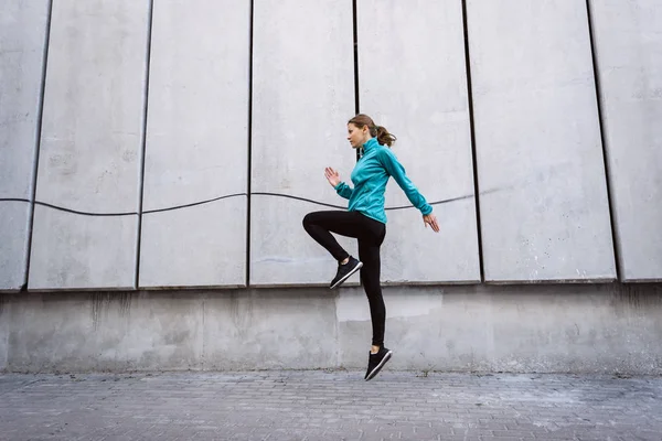 Young adult athlete woman jumping up against wall outdoor — Stock Photo, Image