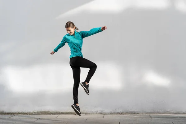 Fiatal felnőtt sportos nő ugrás ellen fal szabadban — Stock Fotó