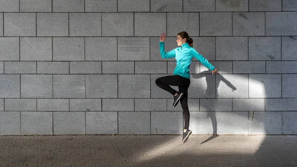 Fiatal felnőtt sportos lány ugrás ellen fal szabadban — Stock Fotó