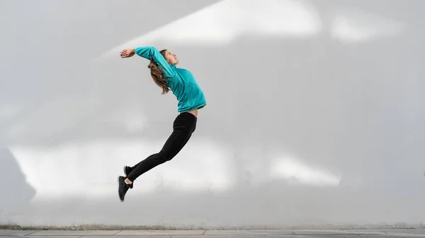 Jeune fille adulte sautant contre le mur extérieur — Photo