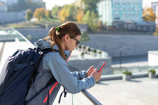 Mujer adulta joven caminando en la ciudad en fin de semana, usando un teléfono inteligente —  Fotos de Stock