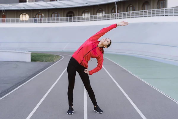 Fiatal felnőtt sportoló nő nyújtózkodik a testét edzés előtt — Stock Fotó