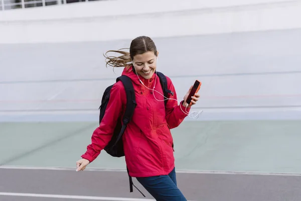 Mladý dospělý sportovní dívka pomocí smartphone, procházky ve městě — Stock fotografie