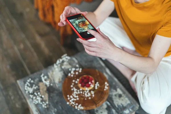 Young adult food stylist woman taking photo on smartphone