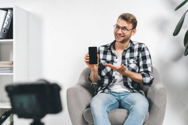 Genç yetişkin başarılı blogcu video kamera kullanıyor, yaratıcı onli