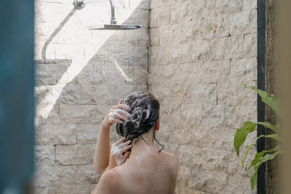 Молодая взрослая девушка принимает душ, стоя в ванной — стоковое фото
