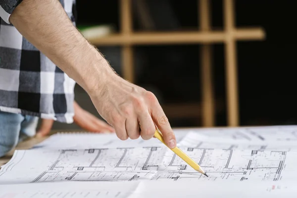 Arquitecto joven adulto trabajando con planos en el estudio del lugar de trabajo —  Fotos de Stock