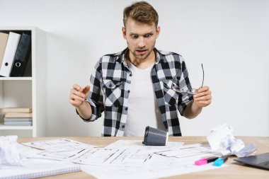 Genç yetişkin proje yöneticisi ve mimar planlarla birlikte profesyonel büroda çalışıyor.